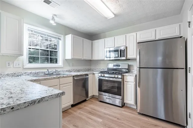 a kitchen with stainless steel appliances granite countertop a refrigerator sink and stove