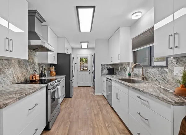 a large kitchen with stainless steel appliances granite countertop a lot of counter space and wooden floors