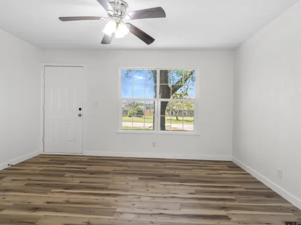 a view of an empty room with window and wooden floor