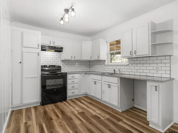a kitchen with kitchen island granite countertop a stove sink and cabinets