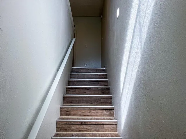 an empty room with wooden floor closet and windows
