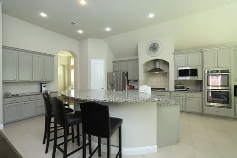 a kitchen with stainless steel appliances granite countertop a table chairs sink and cabinets