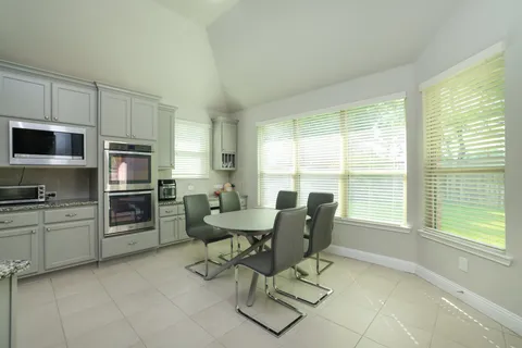 a kitchen with a table chairs microwave and refrigerator
