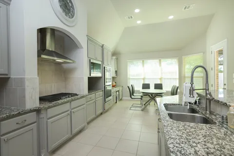 a kitchen with granite countertop a sink and a stove top oven