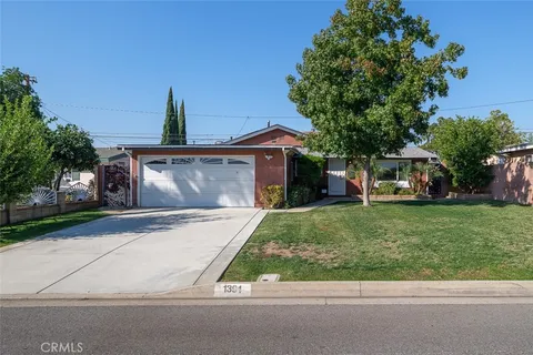 a front view of a house with a garden and trees