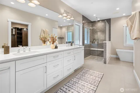 a spacious bathroom with double vanity a toilet a a mirror a vanity and a shower