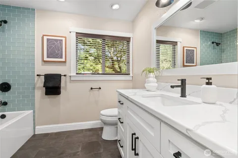 a bathroom with a granite countertop toilet sink and mirror