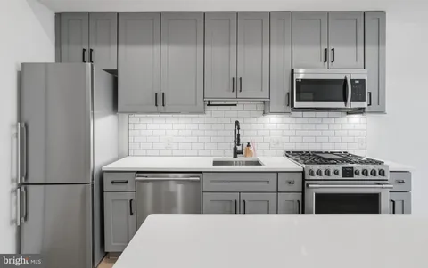 a kitchen with stainless steel appliances a stove a microwave and a sink