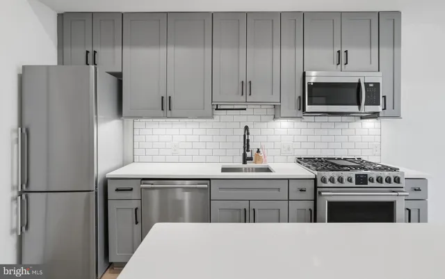 a kitchen with stainless steel appliances a stove a microwave and a sink