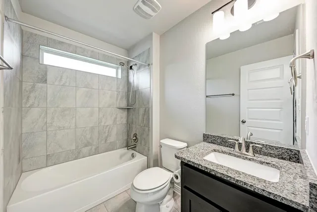 a bathroom with a granite countertop sink toilet mirror and bathtub