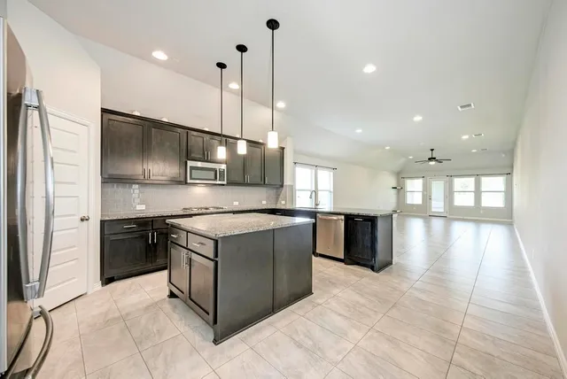 a large kitchen with stainless steel appliances kitchen island granite countertop a refrigerator and a stove top oven