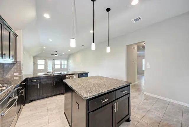 a kitchen with granite countertop a sink stainless steel appliances and cabinets