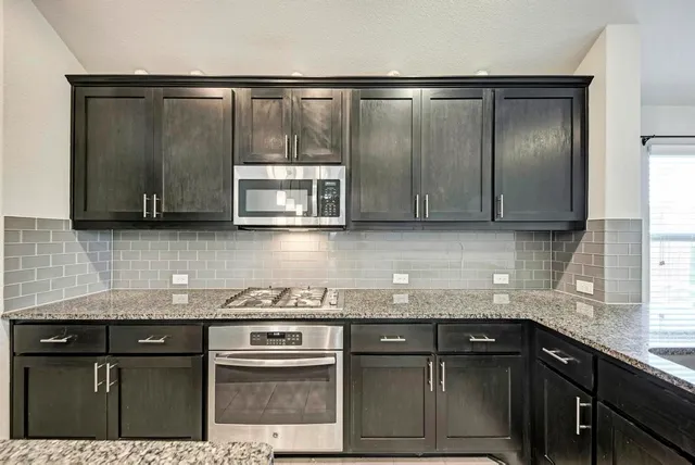 a large kitchen with stainless steel appliances kitchen island granite countertop a large counter top a stove a microwave a sink and a refrigerator