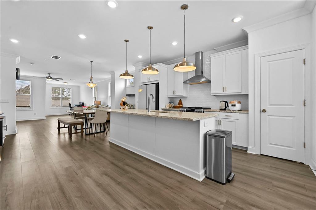 3217 Bartee Walk Suwanee, GA 30024 - Photo 12 of 36 a kitchen with stainless steel appliances granite countertop a stove a refrigerator a oven a sink a dining table and chairs with wooden floor