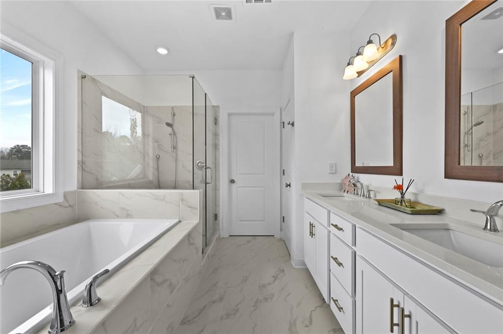 3217 Bartee Walk Suwanee, GA 30024 - Photo 27 of 36 a bathroom with a double vanity sink a large mirror and a bathtub