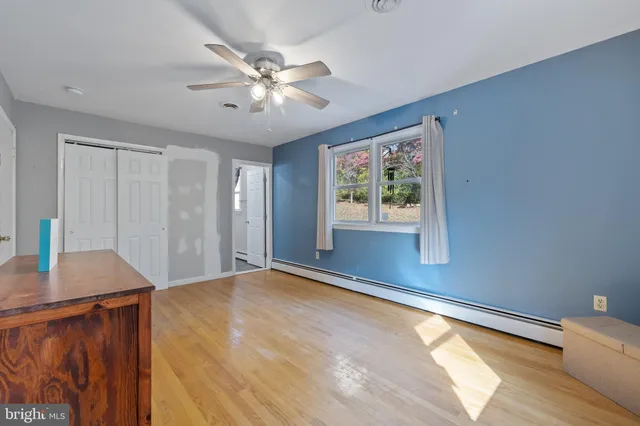 a view of a kitchen with wooden floor a ceiling fan and windows