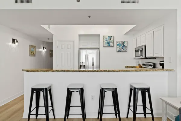 a kitchen with stainless steel appliances granite countertop a table chairs microwave and sink