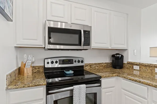 a kitchen with granite countertop white cabinets and stainless steel appliances