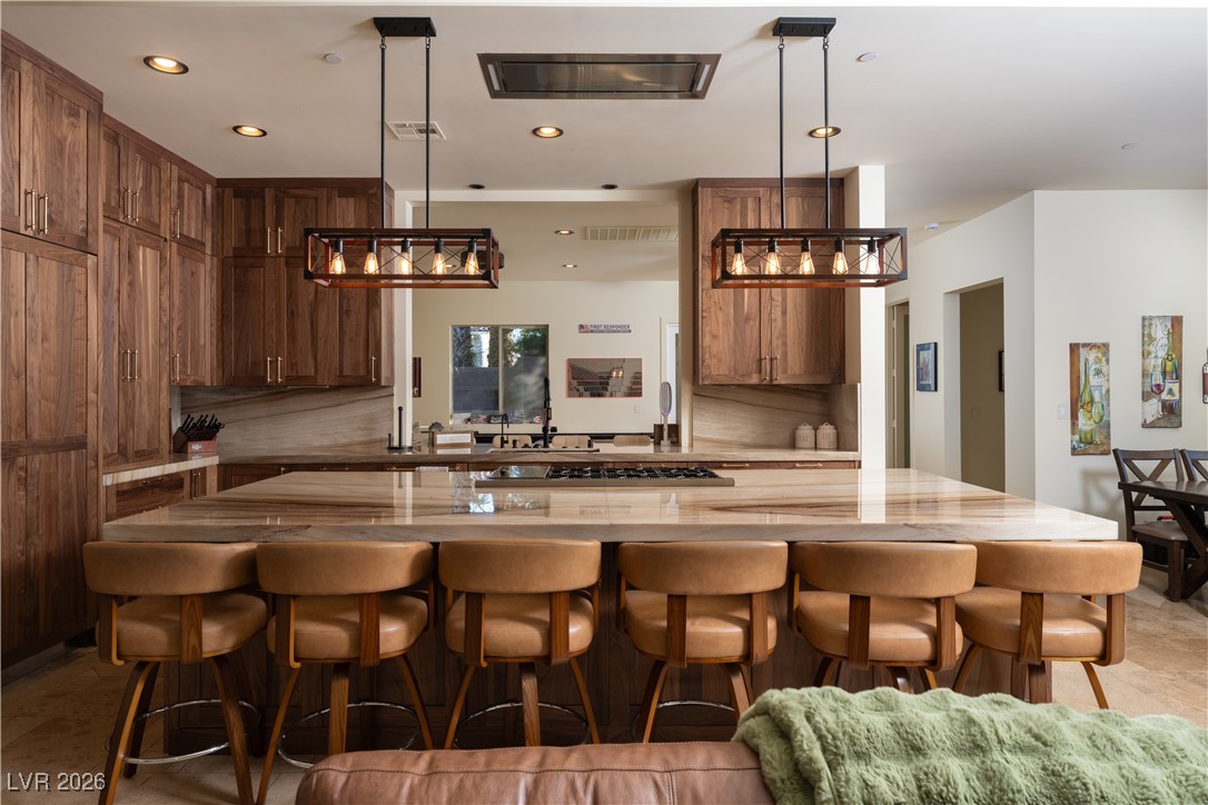 2817 High View Drive Henderson, NV 89014 - Photo 19 of 77 Kitchen with hanging light fixtures, brown cabinets, a breakfast bar area, tasteful backsplash, and recessed lighting