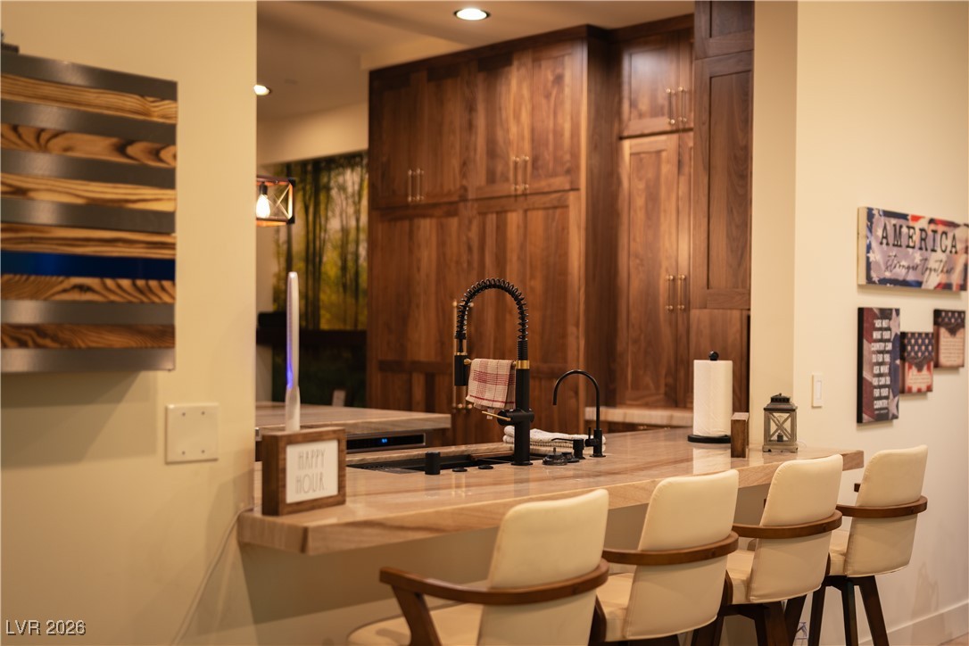 2817 High View Drive Henderson, NV 89014 - Photo 29 of 77 Kitchen featuring light stone counters, brown cabinetry, a breakfast bar, and recessed lighting