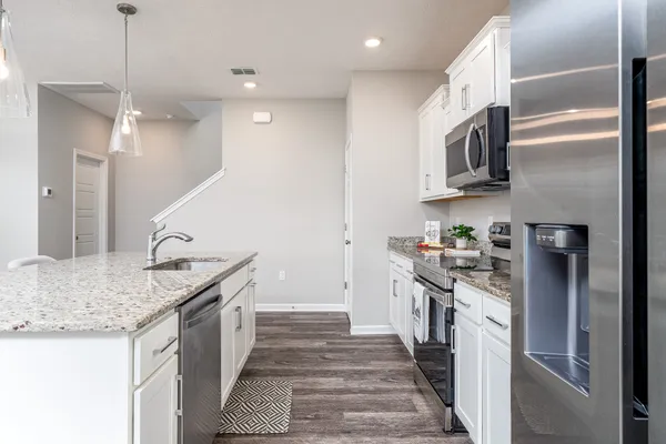 a kitchen with granite countertop a sink and white cabinets with wooden floor
