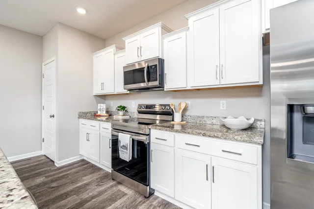 a kitchen with stainless steel appliances granite countertop a sink a stove and a refrigerator