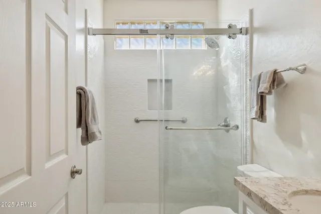 a bathroom with a granite countertop shower a sink and toilet