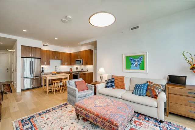 a living room with stainless steel appliances granite countertop a stove top oven a sink dishwasher a dining table and chairs with wooden floor