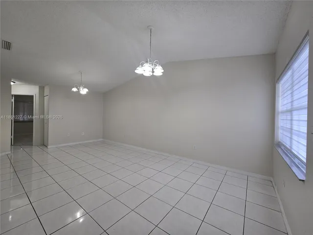 a view of a livingroom with a chandelier fan and kitchen view