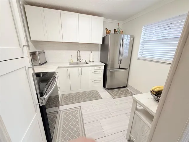 a kitchen with stainless steel appliances a refrigerator a sink a stove and white cabinets