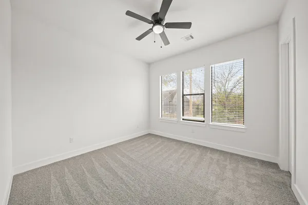 an empty room with windows and fan
