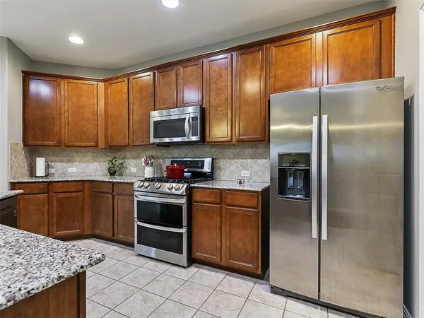 a kitchen with stainless steel appliances granite countertop a refrigerator a stove a sink and dishwasher