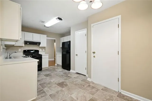 a kitchen with a refrigerator a stove top oven and a sink