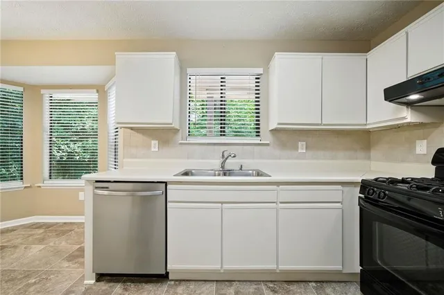 a kitchen with cabinets appliances a sink and a window
