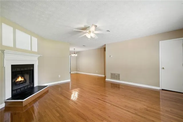 a view of a livingroom with a fireplace a ceiling fan and wooden floor