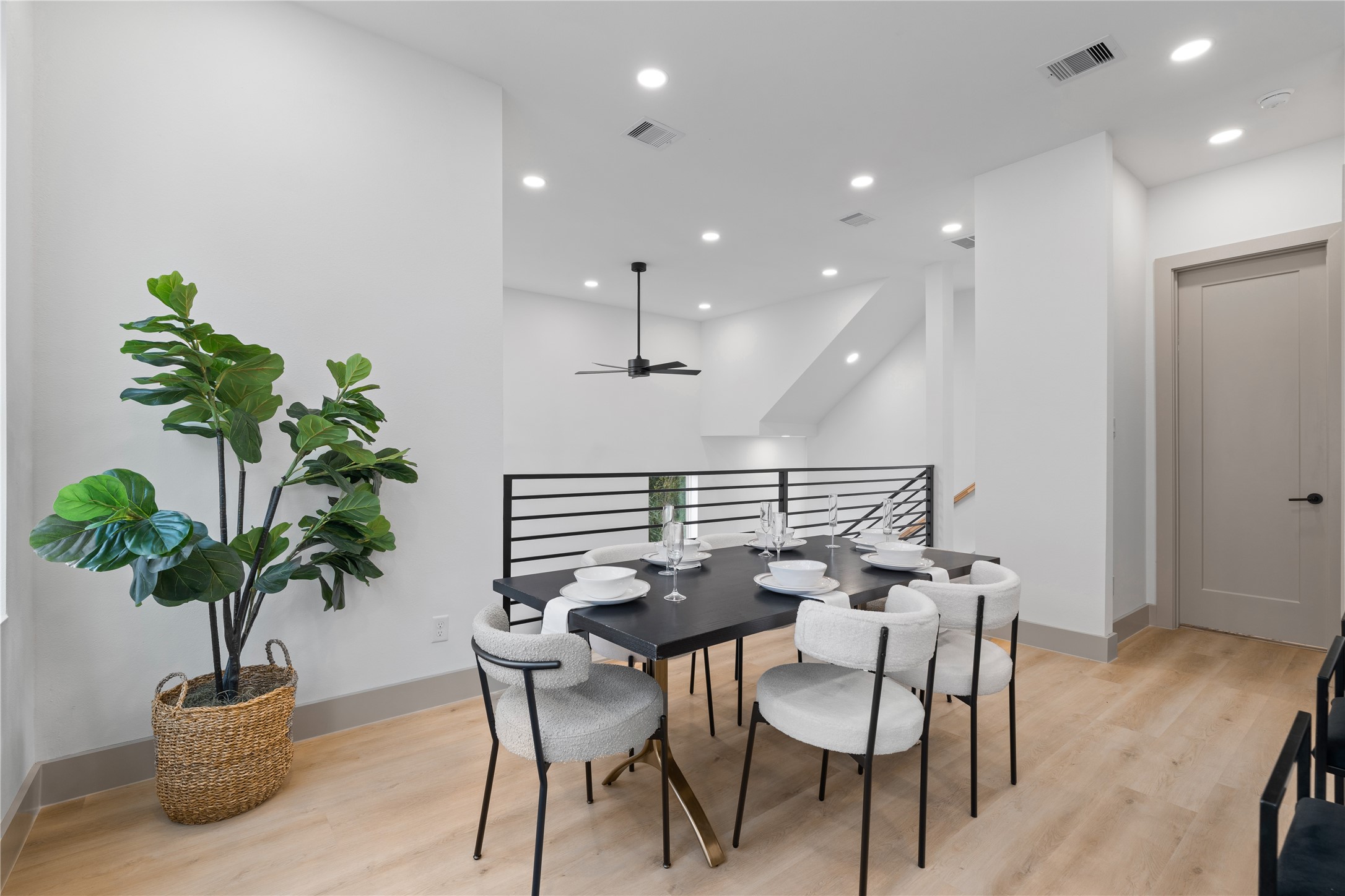 2948 Pitzlin Street Houston, TX 77023 - Photo 9 of 37 Overlooking the dramatic two-story living room, this open dining area features modern railing details, recessed lighting, and wide-plank SPC flooring—blending form and function in an architecturally distinct layout.