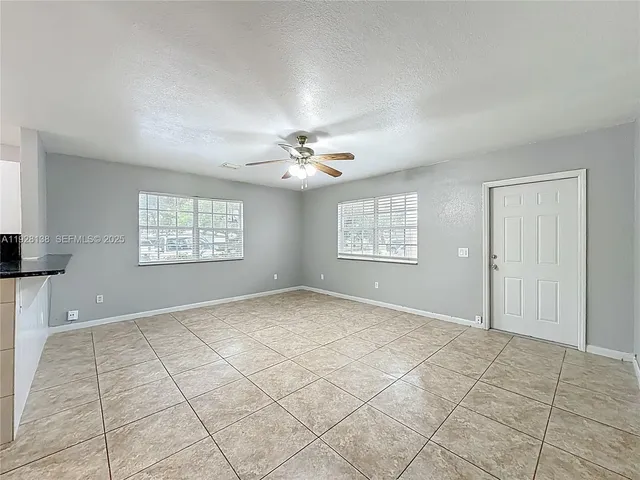 an empty room with windows and fan
