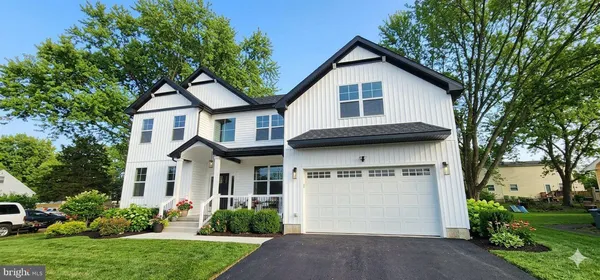 a front view of a house with a garden and trees
