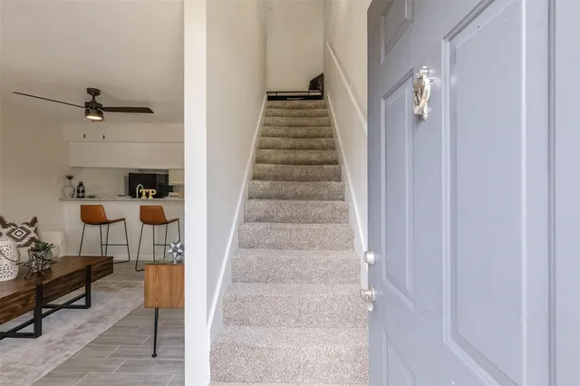a view of staircase with lots of frames on wall and a potted plant