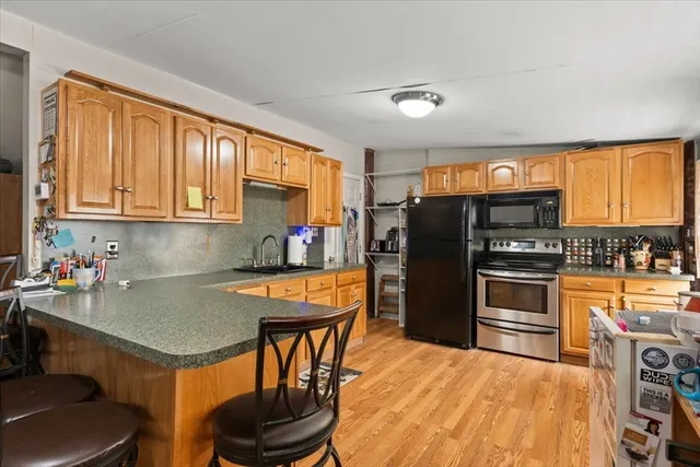 a kitchen with stainless steel appliances granite countertop a refrigerator stove top oven dining table and chairs