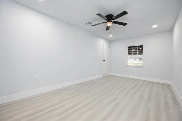 an empty room with window and ceiling fan