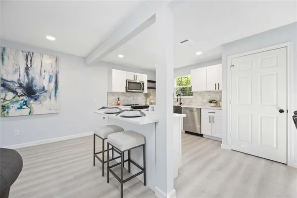 a kitchen with stainless steel appliances kitchen island granite countertop a refrigerator a stove a sink dishwasher and white cabinets with wooden floor