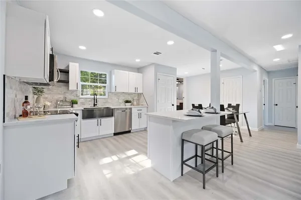 a kitchen with white cabinets and chairs