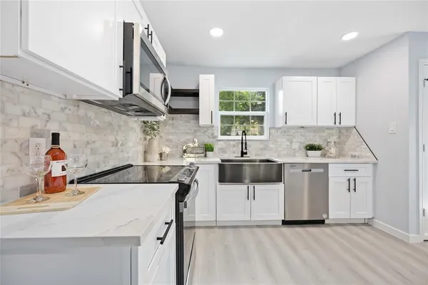 a kitchen with stainless steel appliances kitchen island wooden cabinets a sink a stove a window and a refrigerator