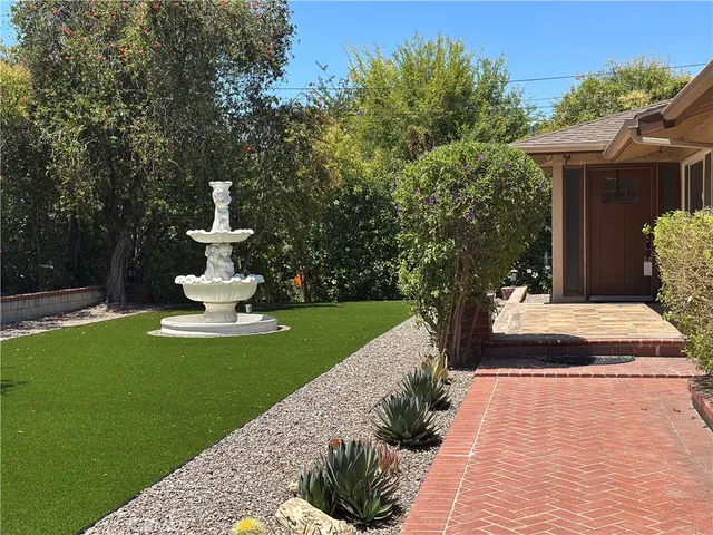 a view of a house with garden and a fountain