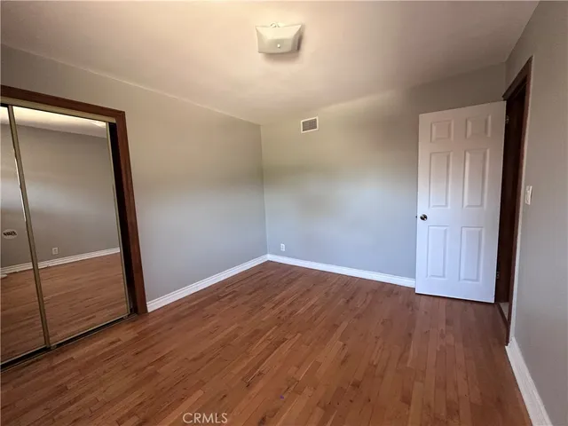 an empty room with wooden floor and mirror