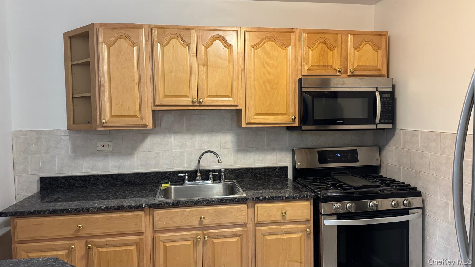 65-35 108th Street, Unit B15 Queens, NY 11375 - Photo 10 of 13 a kitchen with stainless steel appliances granite countertop a sink a stove and microwave