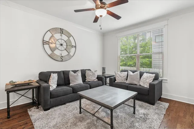 a living room with furniture a clock on wall and a window
