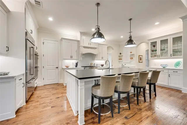 a kitchen with stainless steel appliances granite countertop a sink a stove a refrigerator and wooden floor