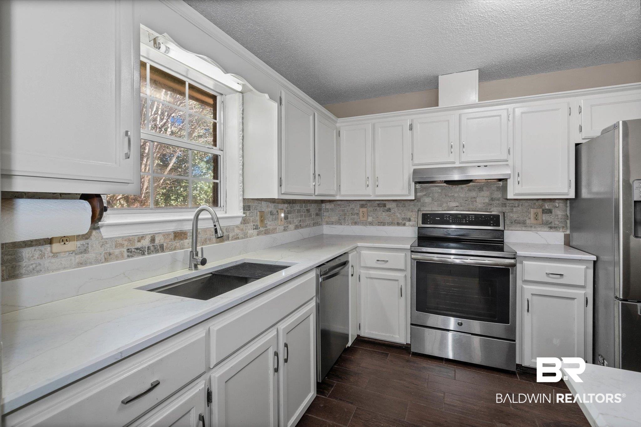 180 Creax Road Axis, AL 36505 - Photo 8 of 35 Kitchen featuring stainless steel appliances, white cabinets, a textured ceiling, and decorative backsplash
